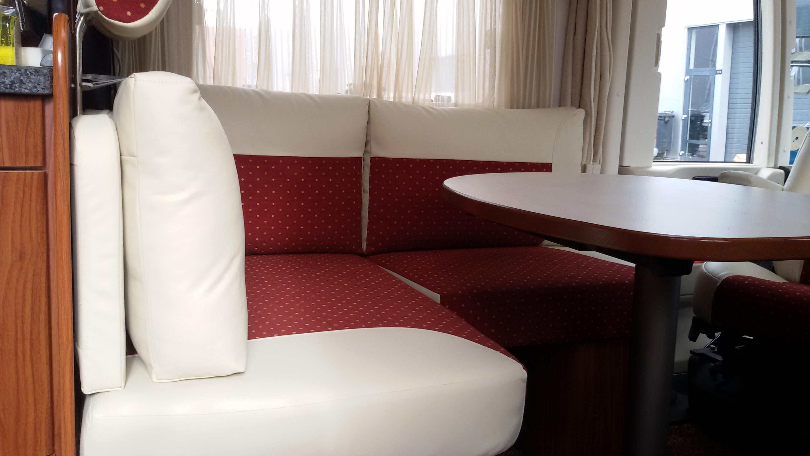 Herstoffeerde camper-zithoek met wit leer en rood accentstof